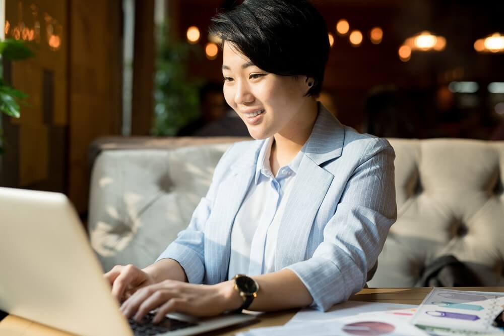 A woman smiling and typing on a laptop